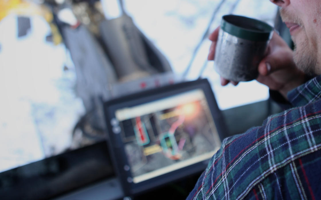 Operator in forestry machine cabin drinking coffee