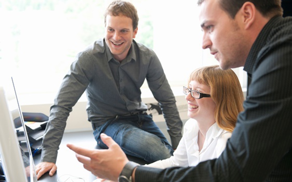 Employees looking at computer screen cooperating.